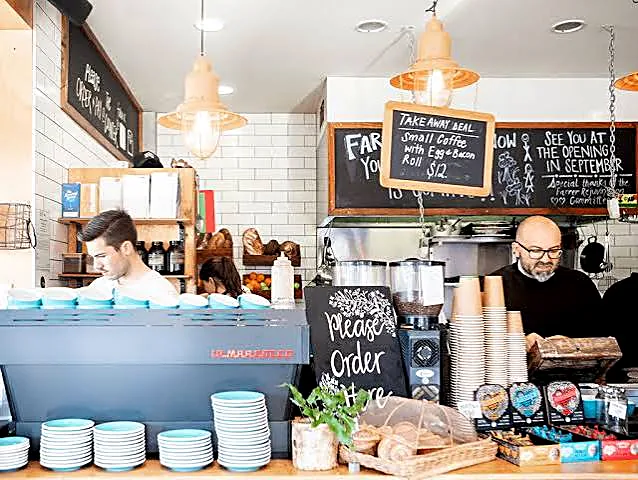 Inside Fox & Bow cafe — coffee bar, chalkboard menu and hanging pendant lights