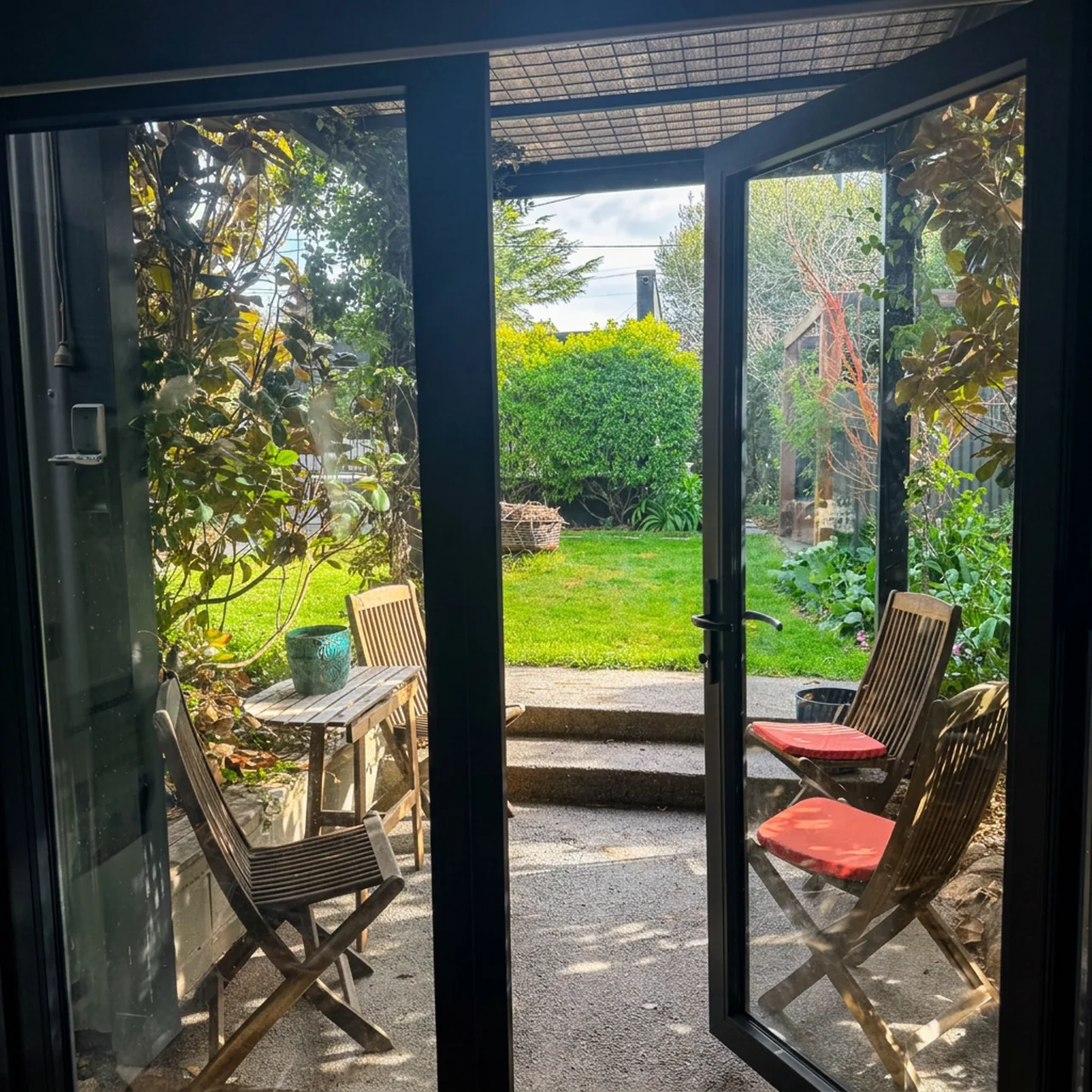 View from inside the studio through open glass doors to the courtyard and garden