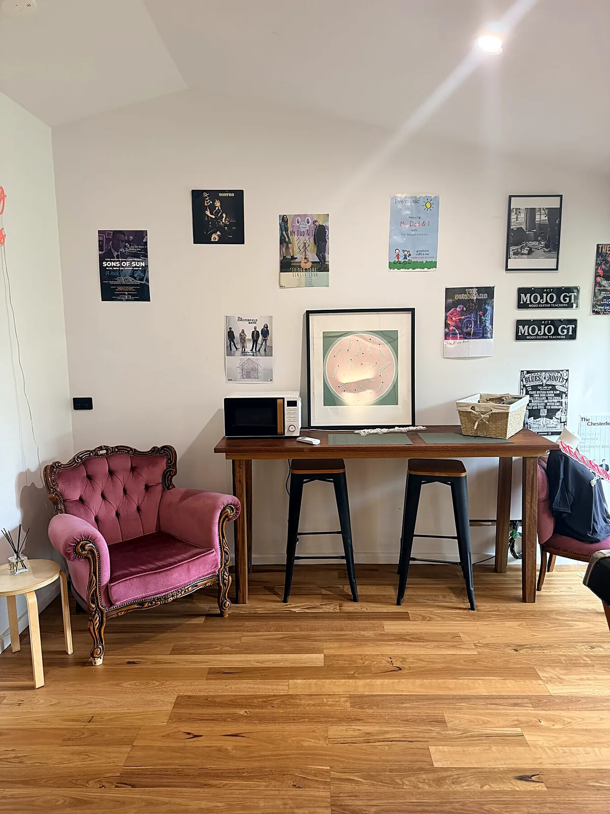 Timber bench with stools, velvet armchair and a wall of live music posters