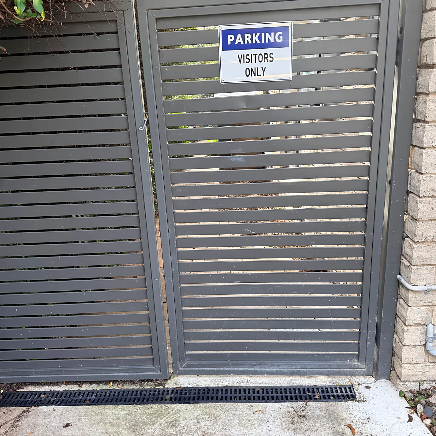 Close view of the grey slat gate with the Parking Visitors Only sign