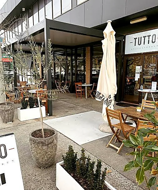 Outdoor seating and potted olive trees outside Tutto Delicatessen at Mawson shops
