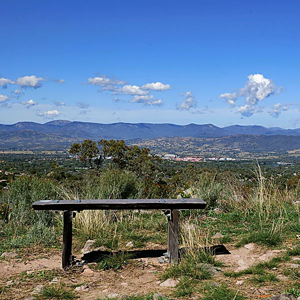 A wooden bench on Farrer Ridge overlooking the Brindabella Ranges and Canberra