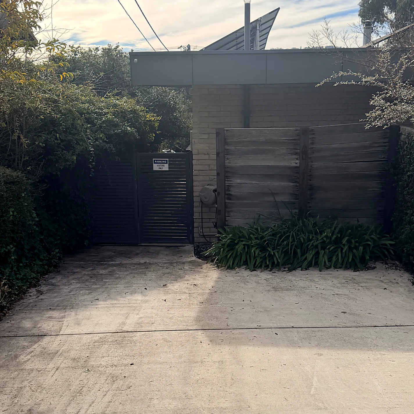 Driveway leading to the grey metal parking gate