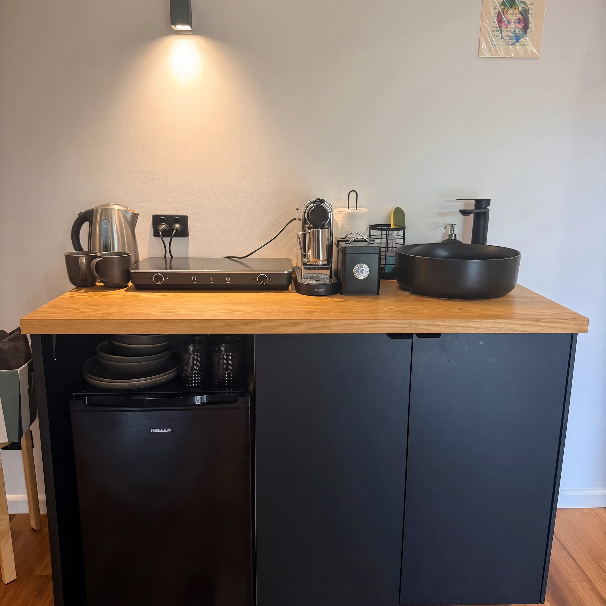 Kitchenette with timber benchtop, induction cooktop, Nespresso machine, kettle, mini fridge and black basin